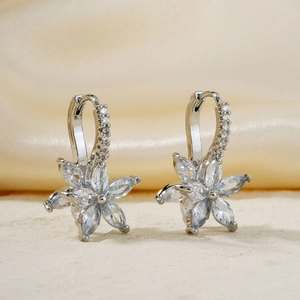 Detail shot of silver lotus earrings with marquise-cut zircons on elegant silk background