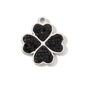 Macro view of four-leaf clover pendant with black stones and silver-tone metal base