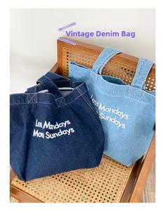 Détail de sacs cabas en jean avec broderie 'Less Mondays More Sundays' sur une chaise vintage