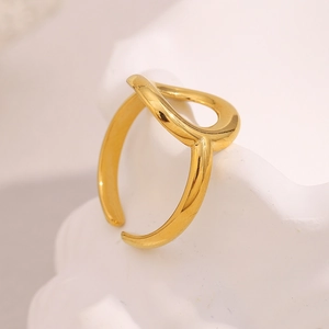 Macro di un anello dorato con cuore traforato su una base decorativa bianca e strutturata