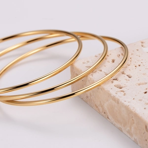 Three-piece minimalist polished gold stainless steel bangles set on stone base