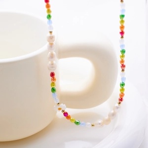 Detailed view of handmade beaded necklace with pearls and flowers on a white mug handle
