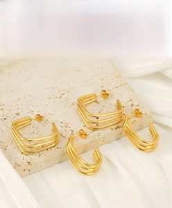 Macro detail of 18K gold plated stainless steel square and oval layered stud earrings