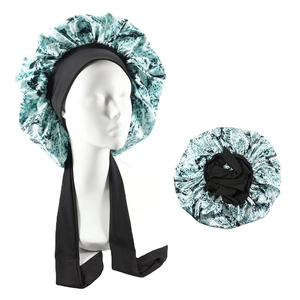 Detail of satin sleep bonnet with wide ties and green abstract pattern on black base