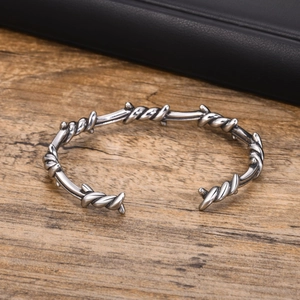 Close-up of silver vintage twisted thorn cuff bracelet on a natural wood surface