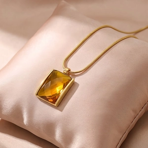 Detailed close-up of 18K gold plated square amber glass pendant on snake chain