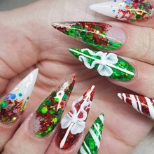 Detailed view of long stiletto press-on nails with Christmas glitter and festive patterns