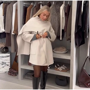 Close-up detail of cream white wool cloak coat with waist belt and luxurious fabric texture