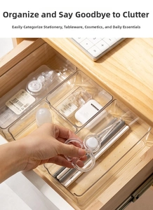 Macro shot of transparent drawer dividers organizing scissors and stationery in a desk drawer