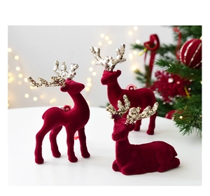 Three burgundy velvet Christmas reindeer figurines with gold glitter antlers on a table