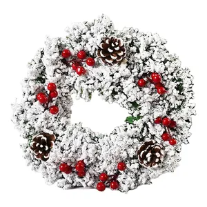 Festlicher Weihnachtskranz mit Flockschnee, roten Beeren und natürlichen Zapfen