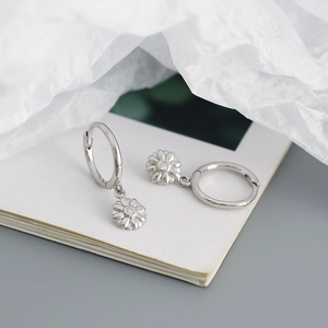 Close-up of small 925 sterling silver daisy hoop earrings on white textured paper