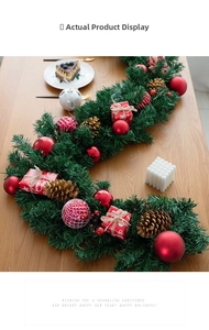 Detailed view of Christmas garland with pine cones and red gift boxes on wooden table