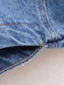 Macro detail of deep blue denim fabric with orange stitching and twill texture
