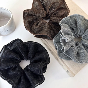 Close-up of sparkling lace scrunchies in brown, gray and black colors on white background