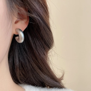 Close-up of matte silver C-shape acrylic hoop earrings on model with high quality finish