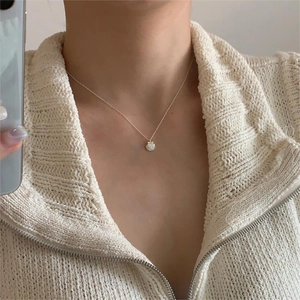 Close-up of S925 sterling silver shell pendant necklace worn on a textured sweater