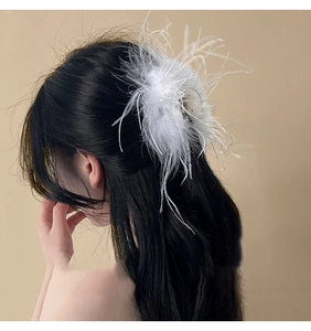 Elegant white ostrich feather hair claw clip shown on model's hair from a side view