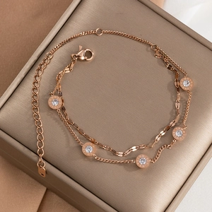 Macro detail of rose gold double-layer bracelet featuring Roman numeral engraved crystal charms