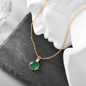 Gold chain necklace with round emerald green gemstone pendant and clear cubic zirconia stones
