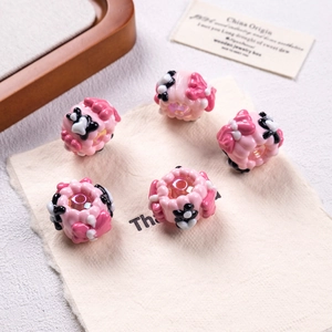 Macro detail of hand-painted pink resin beads with floral bow patterns for DIY jewelry making