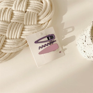 Detail of sweet purple and pink hair clips in oval and wavy shapes on a white card