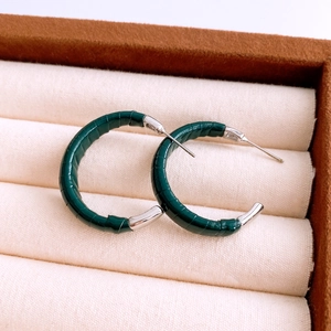 Détail macro de boucles d'oreilles rondes en cuir vert foncé avec tige en argent poli