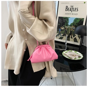 Pink dumpling crossbody bag with magnetic pleats and slim strap on a female model