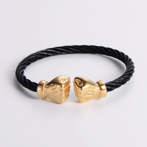 Detail of twisted black cable bracelet featuring gold boxing glove ends in hip hop style