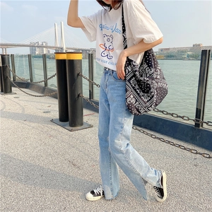 Detail of light blue denim wide leg jeans featuring unique side slits in an outdoor setting