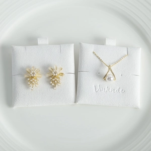 Macro detail of pearl necklace and flower studs on premium white textured display card