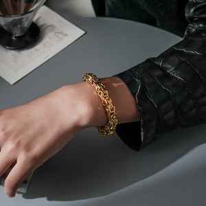 Polished 18K gold plated Byzantine titanium steel chain bracelet worn by a male model