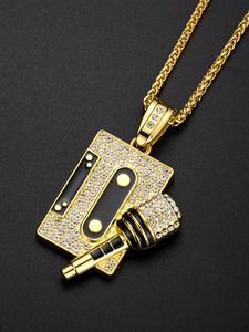 Macro shot of hip hop gold cassette and microphone pendant with crystals and enamel detail