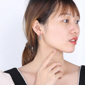 Détail de la boucle d'oreille perlée en forme de U argentée sur un style minimaliste