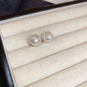 Detailed close-up of bow knot pearl earrings on a soft beige velvet jewelry display tray