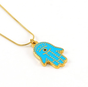 Detail of Hamsa Hand pendant with blue enamel and evil eye on gold snake chain