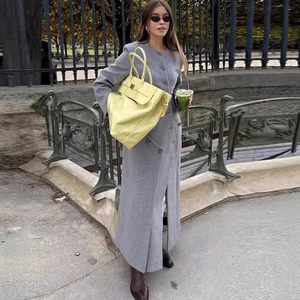 Women's long grey wool coat paired with a vibrant lemon yellow leather handbag outdoors