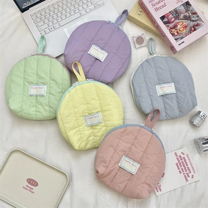 Flat lay of soft quilted shell-shaped cosmetic bags in pastel macarons colors