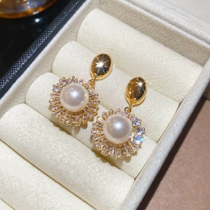 Macro view of 18k gold plated earrings with white pearl and sparkling zircon accents