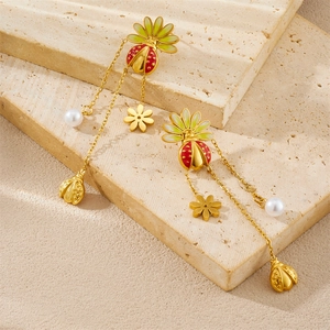 Detailed shot of ladybug and flower earrings with enamel and pearl fringe on stone