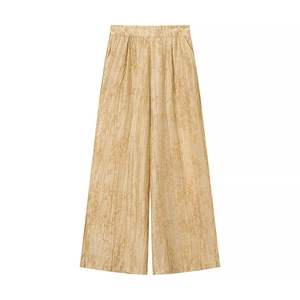 Macro detail of champagne gold floral jacquard fabric on high-waisted wide-leg trousers