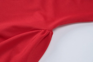Détail d'une robe rouge montrant la texture froncée du tissu et les finitions précises