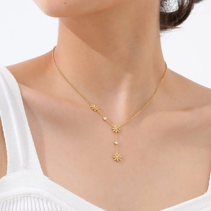 Close-up of golden Y-shaped necklace featuring flower pendants and white zircon accents