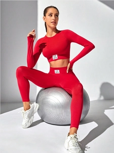 Detail of red ribbed yoga set with GYM WEAR label on high waist pants and long sleeve top