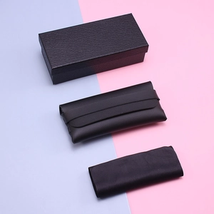 Close-up of black leather sunglasses set including hard box, soft pouch and cleaning cloth