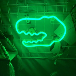 Close-up of a green LED neon dinosaur head light mounted on a white grid wall with USB cable
