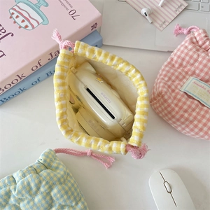Top view of a soft quilted drawstring pouch holding an instant camera on a desk