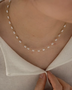 Close-up of elegant gold chain with white rice-shaped pearls on a model neck