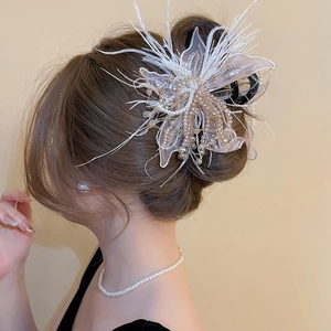 Close-up of lace fabric flower hair claw with elegant pearls and white feather details