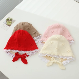 Detail of four knit baby hats with lace trim in red, pink, cream and brown colors